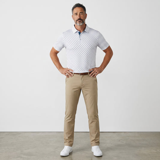 Byron Nelson Copper Point Polo in white with a blue geometric print, paired with khaki trousers and white sneakers.