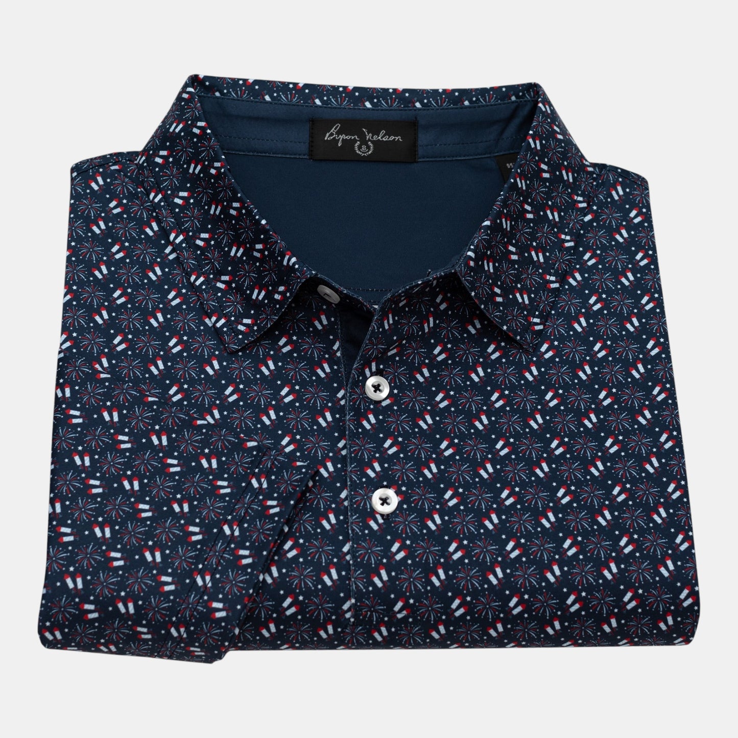 Byron Nelson navy blue polo shirt with all-over red, white, and blue firework pattern. Made from polyester and spandex blend.