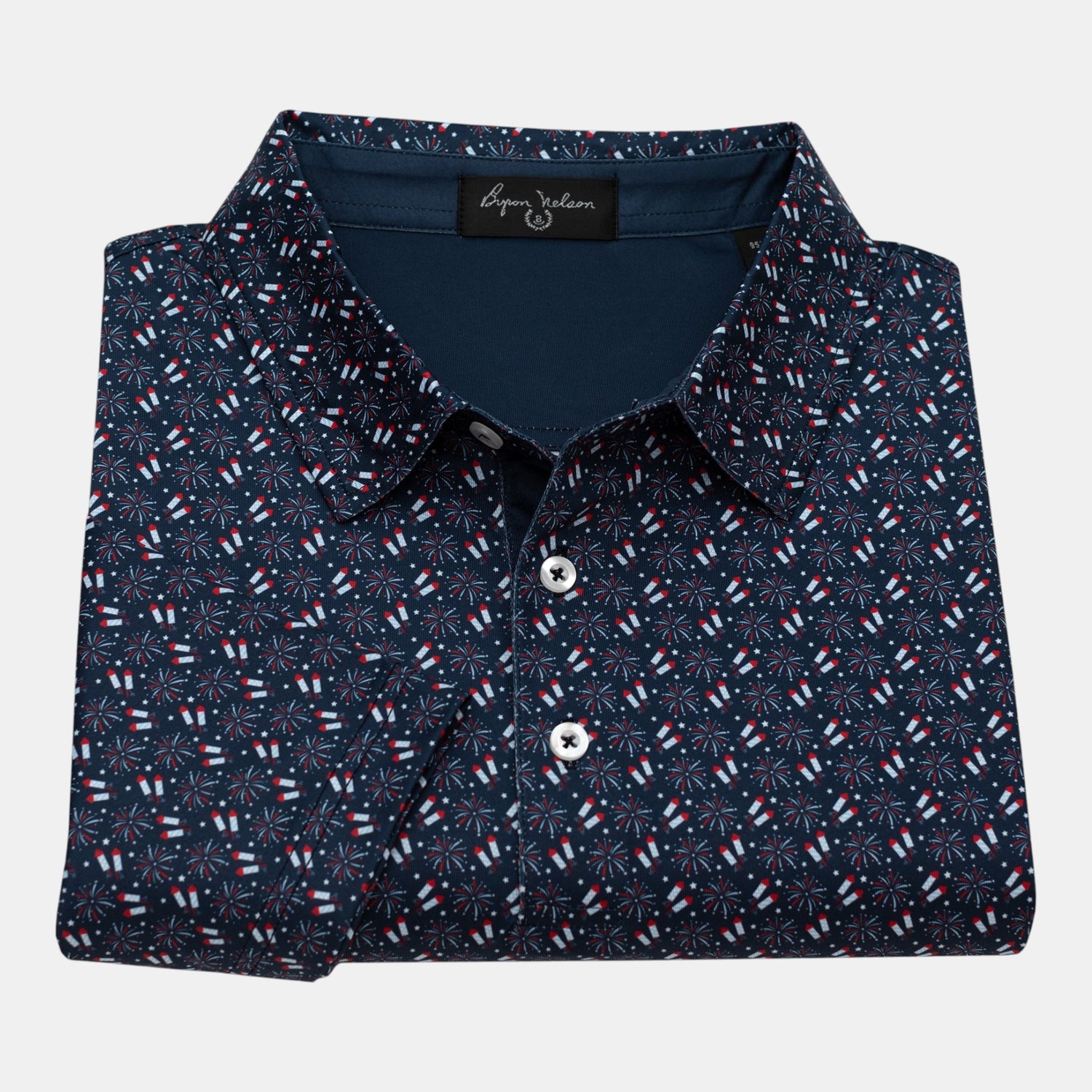 Byron Nelson navy blue polo shirt with all-over red, white, and blue firework pattern. Made from polyester and spandex blend.