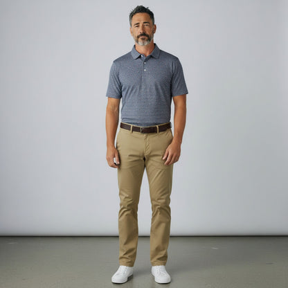 Byron Nelson Midnight Mesh golf polo in dark blue with a subtle pattern, paired with khaki trousers and white sneakers.