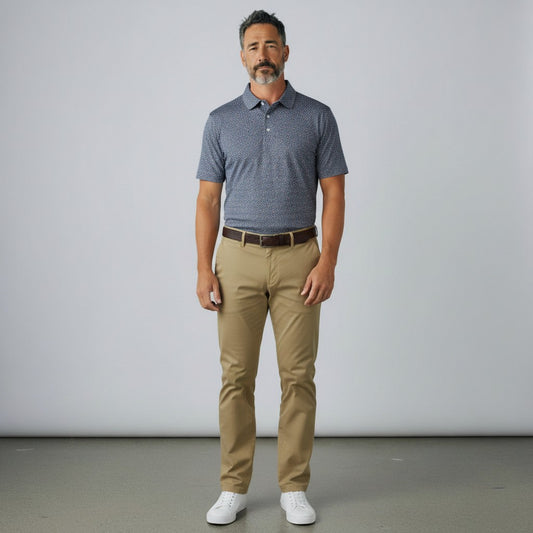 Byron Nelson Midnight Mesh golf polo in dark blue with a subtle pattern, paired with khaki trousers and white sneakers.